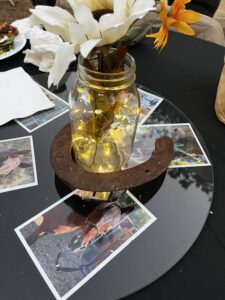 A mason jar with fairy lights and a horse shoe surrounded by pictures of horses